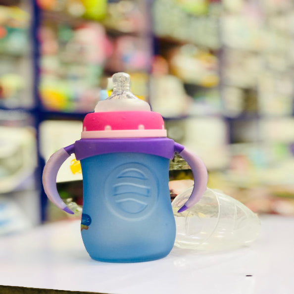 Blue and purple baby bottle with pink cap on a blurred store shelf background