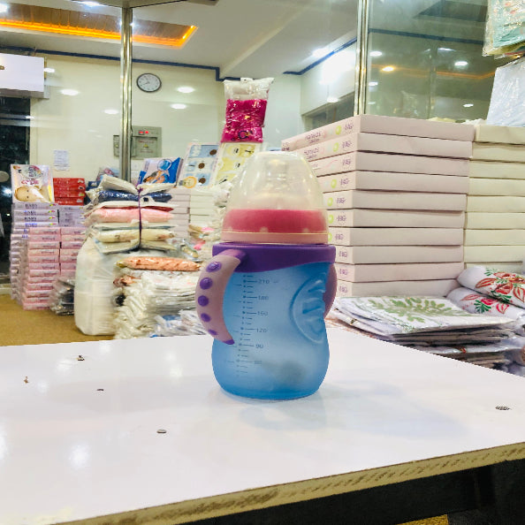 Blue and purple baby bottle with pink handle on a counter in a store setting