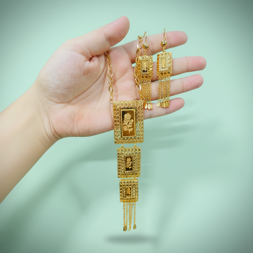 Gold jewelry set held in a hand against a light green background
